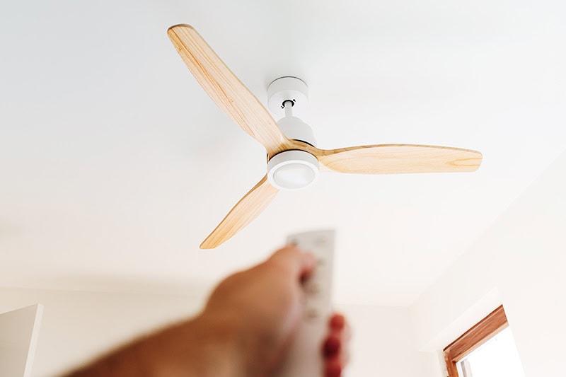 A person using a remote to turn on a ceiling fan