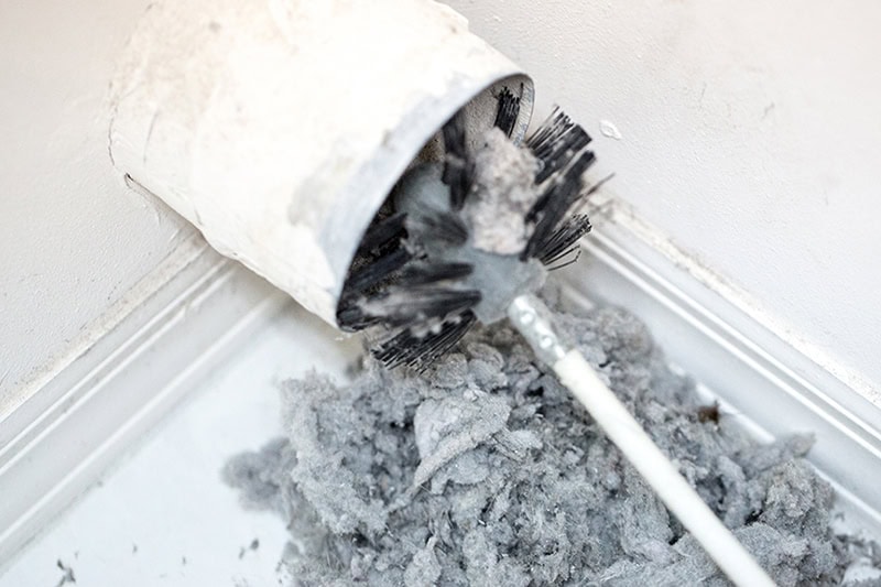 Dry Vent Cleaning. Photo of a brush cleaning out a dryer vent full of lint.